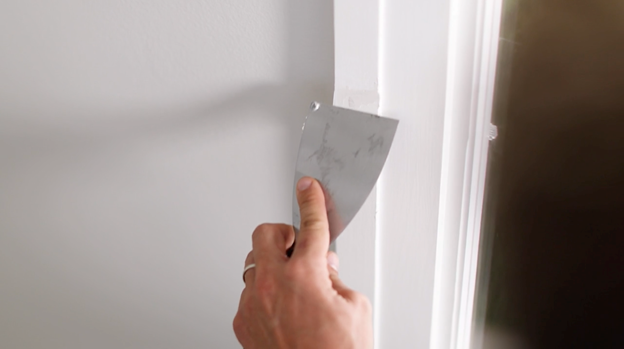 Hand using a scraper on trim.